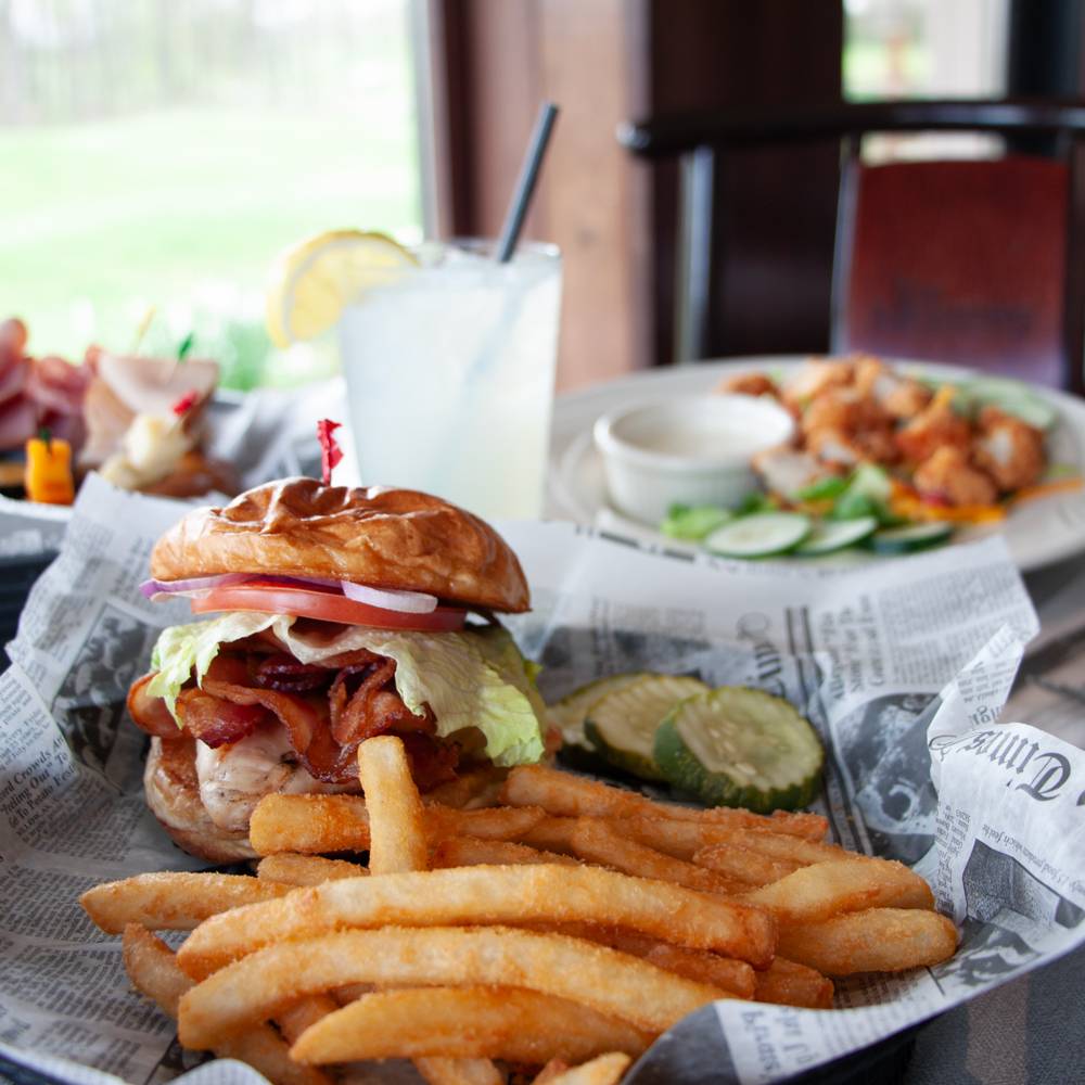 Burger and fries in a basket with other meals in the background